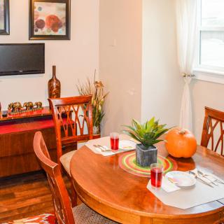 A cozy dining room setup featuring a wooden table with chairs, adorned with a pumpkin and potted plant as centerpiece decor.