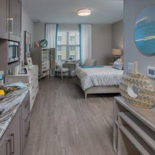 A modern studio apartment featuring a kitchenette and a cozy bedroom area with stylish decor.