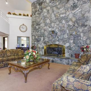 A cozy living room with a stone fireplace, patterned sofas, and a coffee table adorned with decorative flowers.