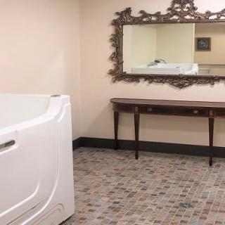 A spacious bathroom with a walk-in bathtub, ornate mirror, and tiled flooring.