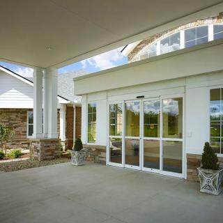 A covered entrance to a modern building with glass doors and decorative plants.