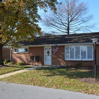 A charming single-story brick house with a well-kept front yard and an American flag displayed.
