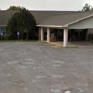 A view of a building with a parking lot in front.