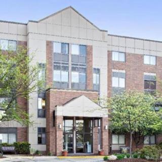 A four-story residential building with a brick facade and surrounding trees.
