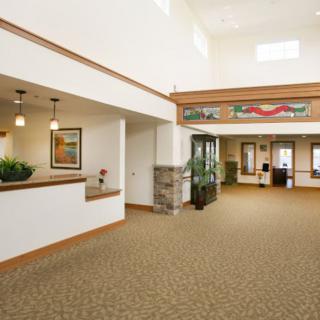 A spacious and modern office lobby with a reception desk and carpeted floor.