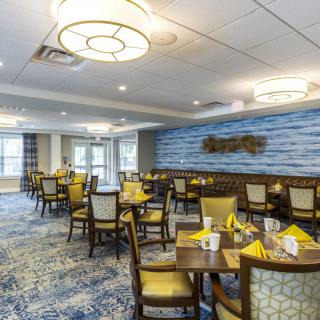 A well-decorated dining area with neatly arranged tables and chairs, featuring elegant lighting and stylish decor.