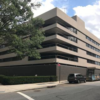 A modern, multi-story building with a minimalist design located on a street corner.