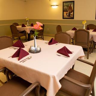 A neatly set dining area with tables, chairs, and folded napkins.