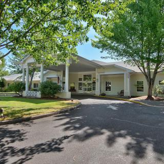 A well-lit building entrance surrounded by lush trees and landscaping.