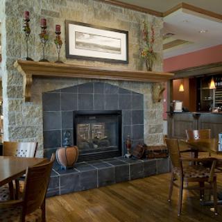 A cozy dining space featuring a stone fireplace and wooden tables, perfect for enjoying meals in a warm ambiance.