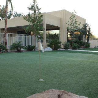 A view of a modern house with a well-maintained lawn and surrounding greenery.