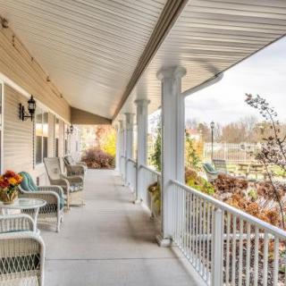A cozy covered porch with seating, overlooking a serene autumn landscape.