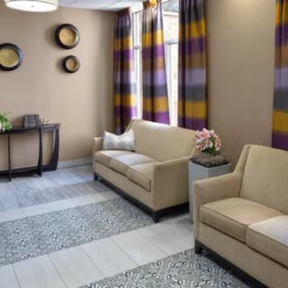 A modern living room with beige sofas, colorful striped curtains, and decorative wall art.