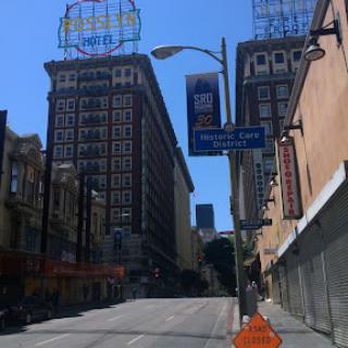 A view of a city street featuring tall buildings and clear blue skies.