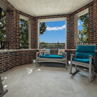 A cozy porch with comfortable seating and a scenic view through brick-framed windows.