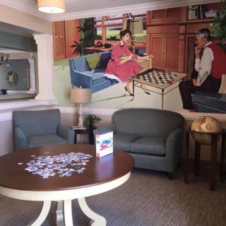 A cozy seating area with a retro mural and a table featuring a puzzle in progress.