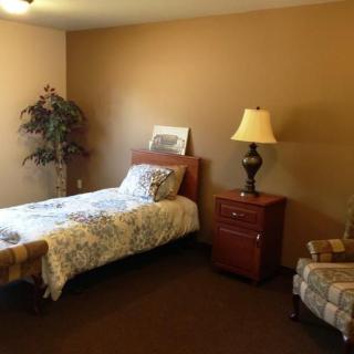 A cozy bedroom with a single bed, nightstand, and lamp.