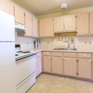 A clean kitchen interior with light wood cabinets and white appliances.