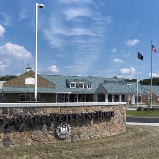 A visitor center with an entrance sign and flags against a partly cloudy sky.