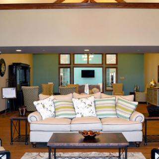 A modern living room with a cozy sofa and decorative pillows, featuring an open layout with a dining area in the background.