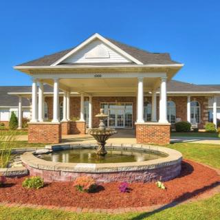 A grand building entrance with a central fountain surrounded by well-maintained landscaping.