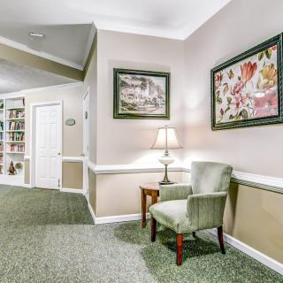 A cozy hallway with a chair, side table, and decorative paintings on the wall.
