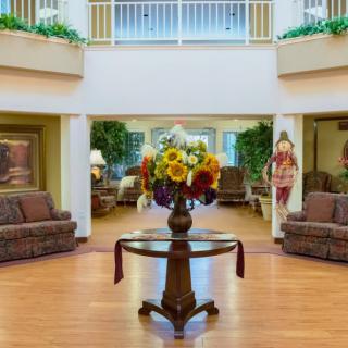 A welcoming lobby area featuring a central table with a floral arrangement, surrounded by comfortable seating.