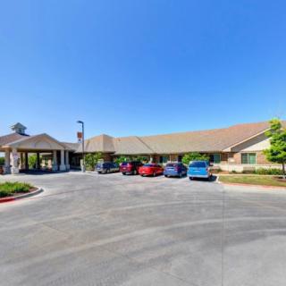 A wide view of a building with a parking lot and several cars under a clear blue sky.