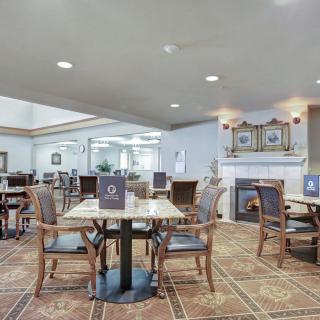 A cozy dining area with multiple tables and chairs, featuring a fireplace and elegant decor.