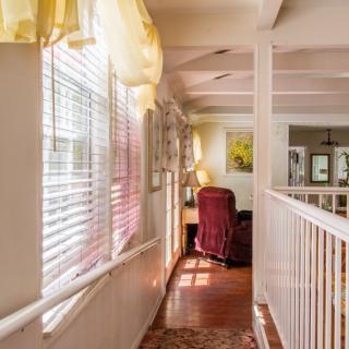 A sunlit hallway with a desk and chair by the window.