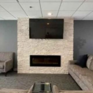 A modern living room featuring a mounted television above a stone fireplace, flanked by comfortable sofas.