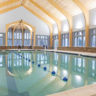 A spacious indoor swimming pool with modern architectural features and soft lighting.