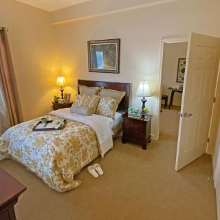 A cozy bedroom with a neatly made bed, warm lighting, and elegant decor.