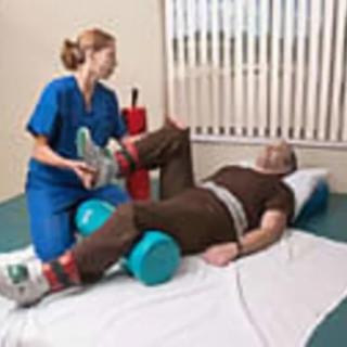 A physical therapist assisting a patient with leg exercises during rehabilitation.