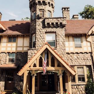A beautiful castle-like mansion featuring a stone facade and a decorative tower.