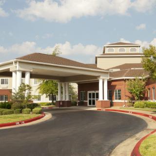 A large building with a covered entrance and circular driveway under a partly cloudy sky.