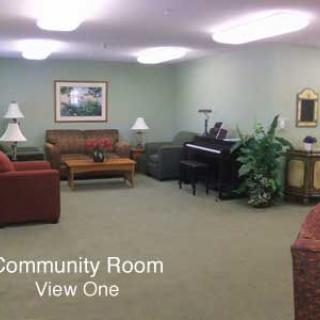 A comfortable community room with sofas, a piano, and cozy lighting.