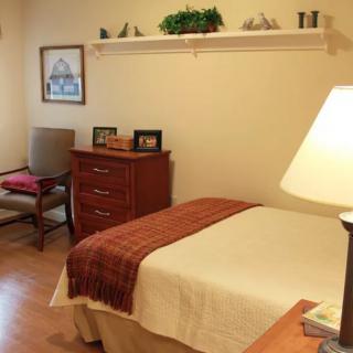 A cozy bedroom with a neatly made bed, a bedside lamp, and simple decor.