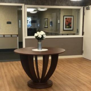 A wooden table with a vase of flowers in a lobby area.