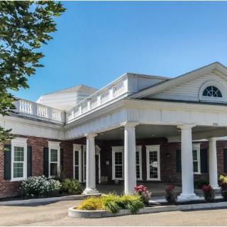A traditional building with columns and a landscaped entrance under a clear blue sky.