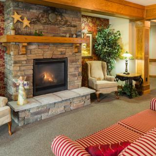 A cozy living room features a stone fireplace, comfortable seating, and warm decor.