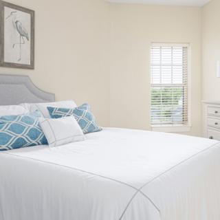 A bright and airy bedroom with a neatly made bed featuring blue patterned pillows.