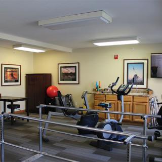 A rehabilitation room equipped with exercise machines and parallel bars.