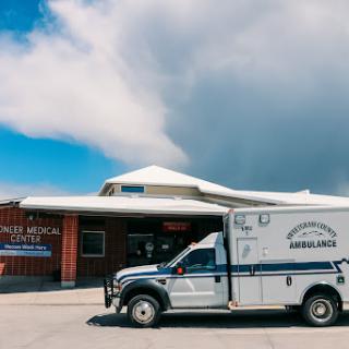 An ambulance parked outside a medical facility under a cloudy sky.