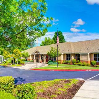 A sunny day outside a single-story office building with surrounding greenery and a well-maintained parking area.