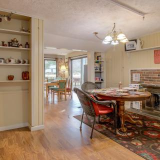 A cozy dining room with an open floor plan featuring a brick fireplace and elegant chandelier.