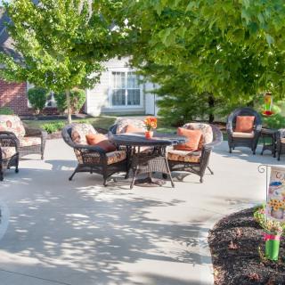 A sunny outdoor patio area with comfortable furniture set amidst greenery.