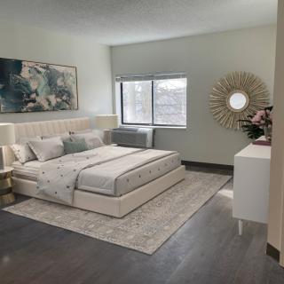 A modern and elegantly decorated bedroom with light tones, featuring a comfortable bed, decorative artwork, and ample natural light.