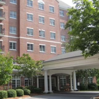 A multi-story brick building with a covered entrance and surrounding greenery.