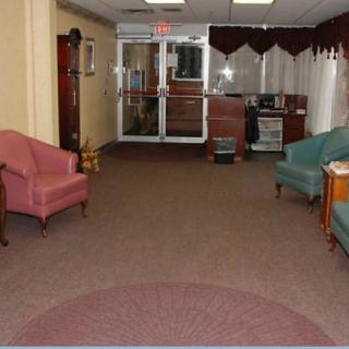 A lobby seating area with chairs and a carpet leading to an entrance.